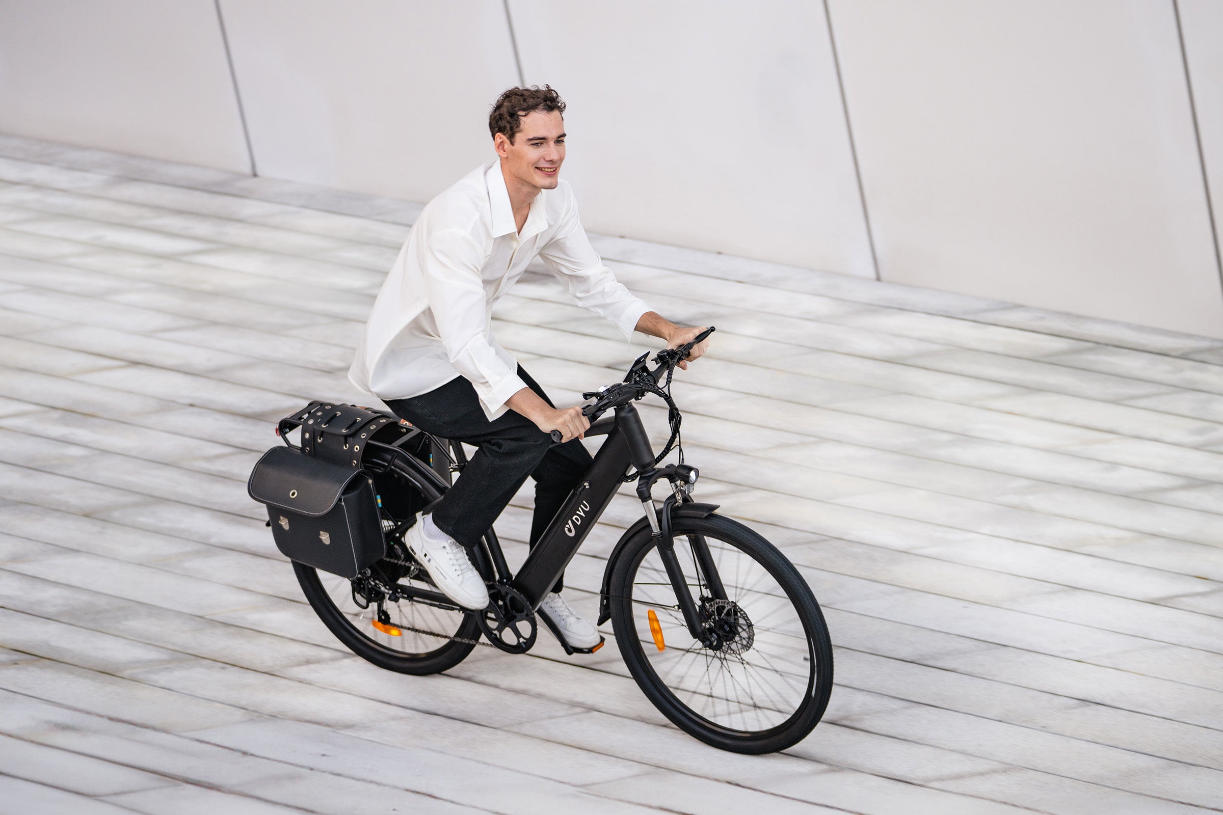 Uomo su bicicletta elettrica DYU C5 nera con portapacchi in ambiente urbano. Uomo su bicicletta elettrica DYU C5 nera con portapacchi in ambiente urbano.