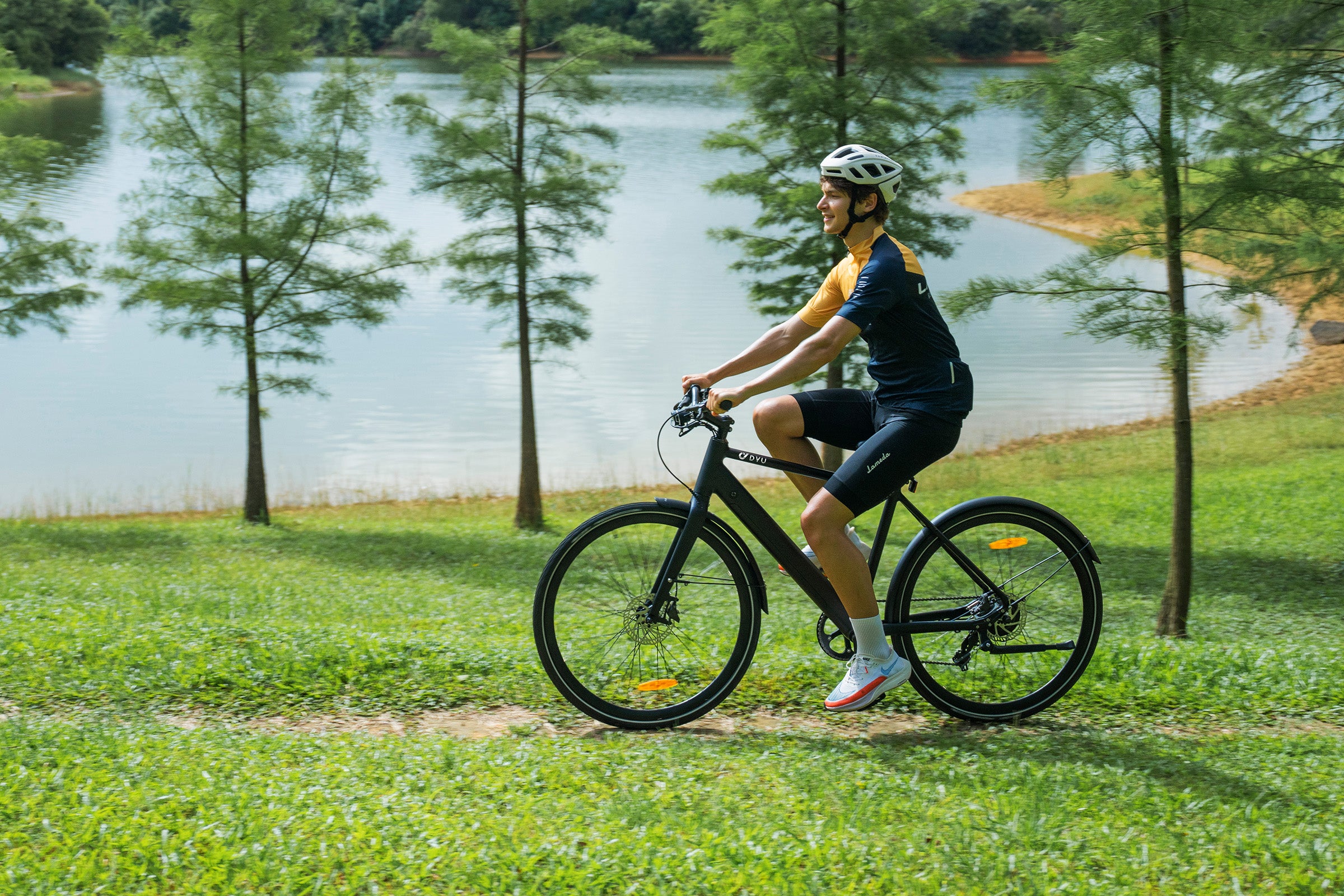 Uomo in maglietta gialla che pedala il DYU Stroll 1 elettrico vicino a un lago. Uomo in maglietta gialla che pedala il DYU Stroll 1 elettrico vicino a un lago.
