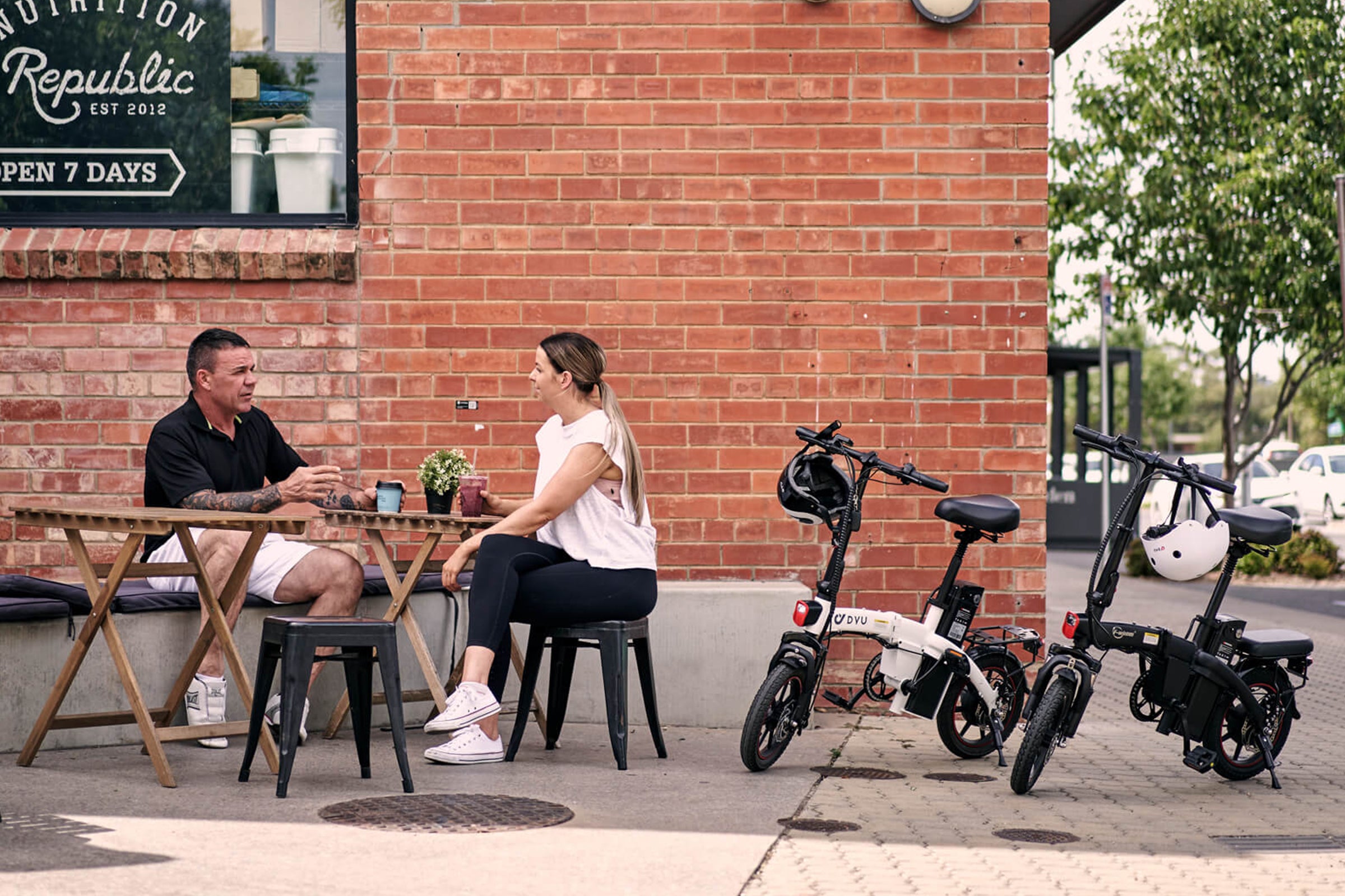 Persone al tavolo con biciclette elettriche DYU C6 in un ambiente urbano. Persone al tavolo con biciclette elettriche DYU C6 in un ambiente urbano.
