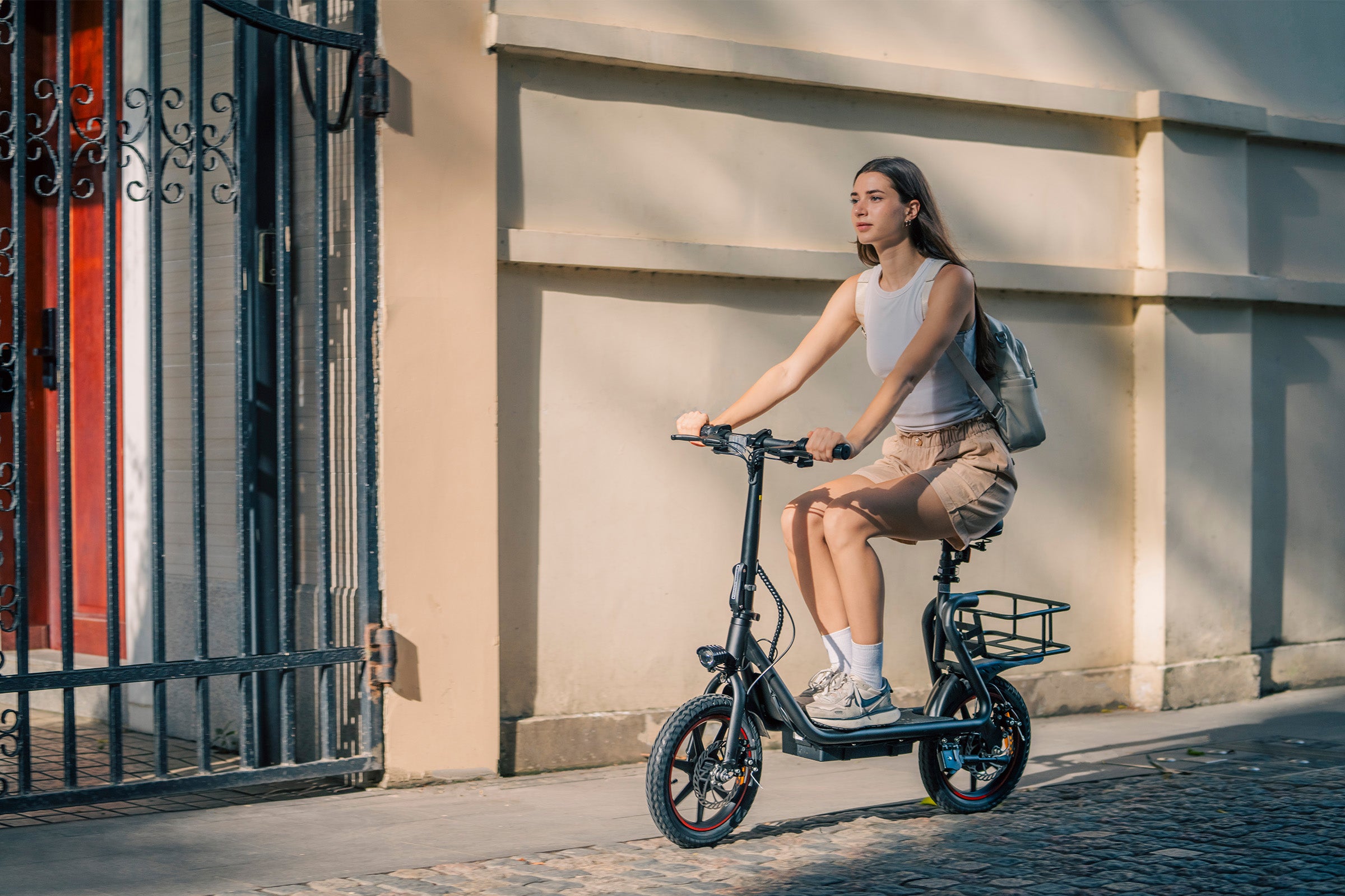 Donna in bicicletta sulla DYU C4 pieghevole nera con cestino, ideale per spostamenti urbani. Donna in bicicletta sulla DYU C4 pieghevole nera con cestino, ideale per spostamenti urbani.