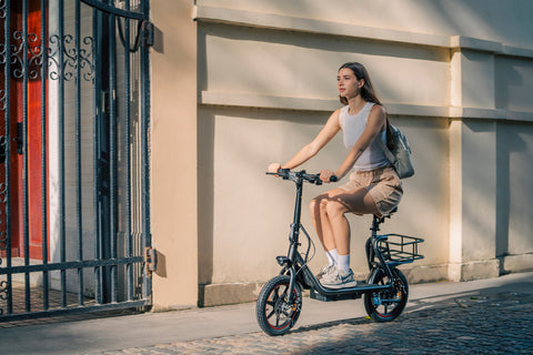 Donna in bicicletta sulla DYU C4 pieghevole nera con cestino, ideale per spostamenti urbani. Donna in bicicletta sulla DYU C4 pieghevole nera con cestino, ideale per spostamenti urbani.
