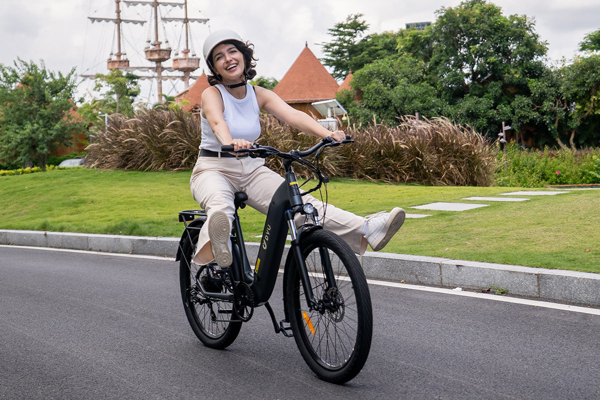 Donna felice che pedala sulla bicicletta elettrica DYU C1 grigia in un parco. Donna felice che pedala sulla bicicletta elettrica DYU C1 grigia in un parco.