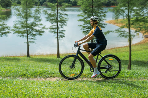 Uomo in maglietta gialla che pedala il DYU Stroll 1 elettrico vicino a un lago.