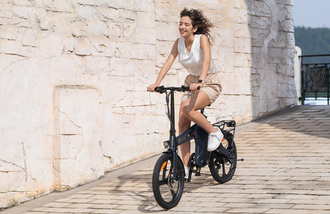 Donna sorridente che guida la bicicletta elettrica D3F DYUcycle su pavimentazione urbana.